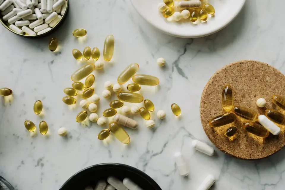 Several supplement bottles and loose capsules arranged on a kitchen counter